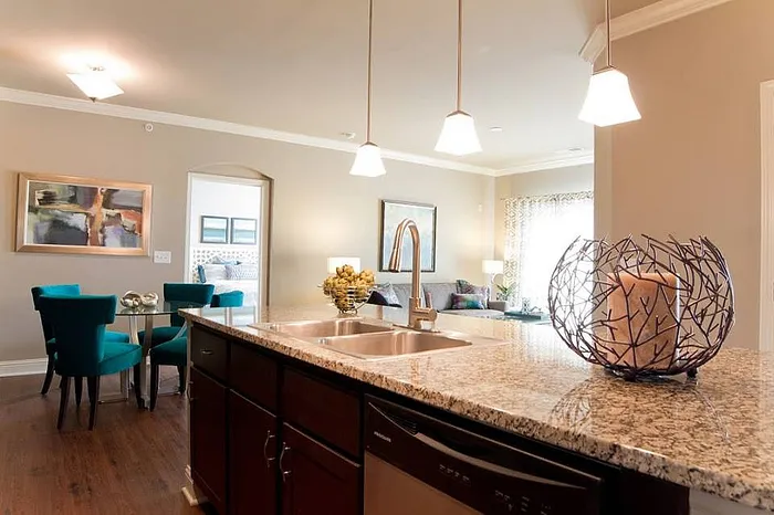 Modern open-plan living space featuring a sleek granite countertop island, elegant lighting, and a cozy dining area.