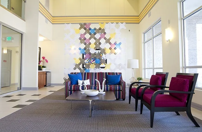 Modern lobby with vibrant decor featuring colorful wall art, striped sofa, and elegant armchairs, offering a welcoming and stylish ambiance.