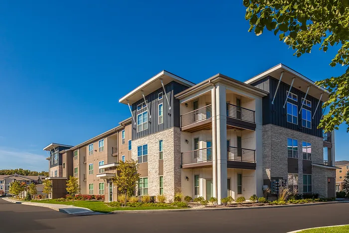Modern apartment community with stylish architecture, featuring large windows and private balconies, surrounded by lush landscaping.