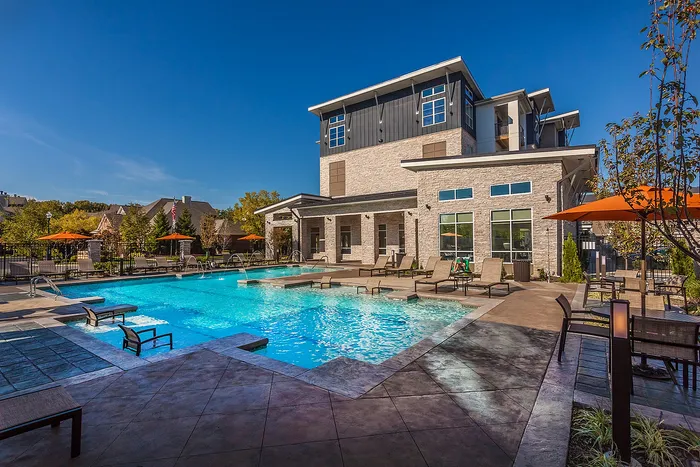 Luxurious apartment community with a sparkling pool, with relaxing sun loungers.