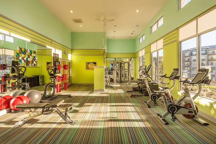 Vibrant fitness center with modern equipment, sunny windows, and colorful decor for an energetic workout experience.