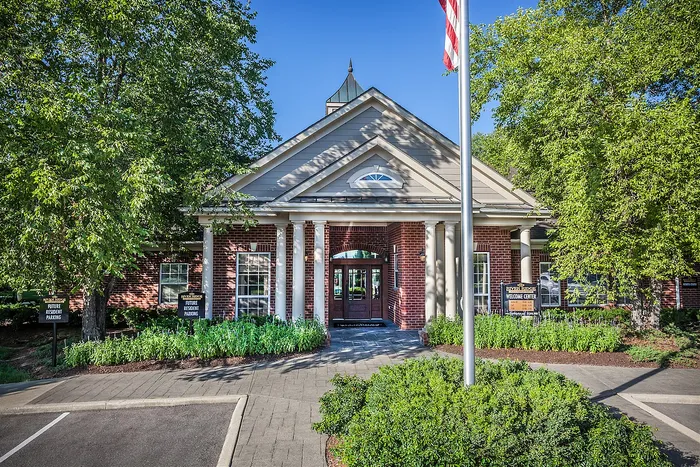 Picturesque brick welcome center with elegant columns, surrounded by lush greenery and welcoming pathways.