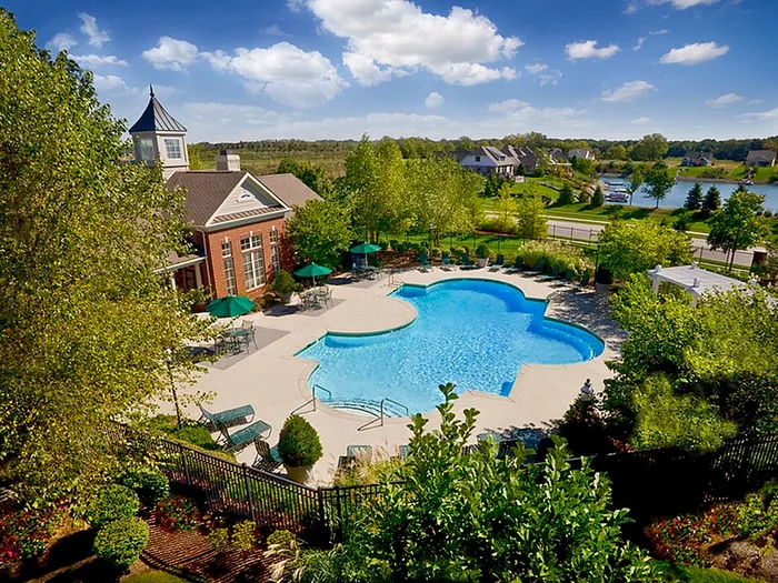 Charming residential apartment community featuring a beautifully designed pool surrounded by lush greenery and elegant landscaping.