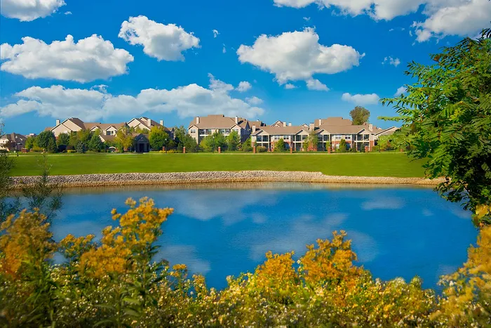 Charming apartment community nestled by a serene lake with vibrant landscaping.