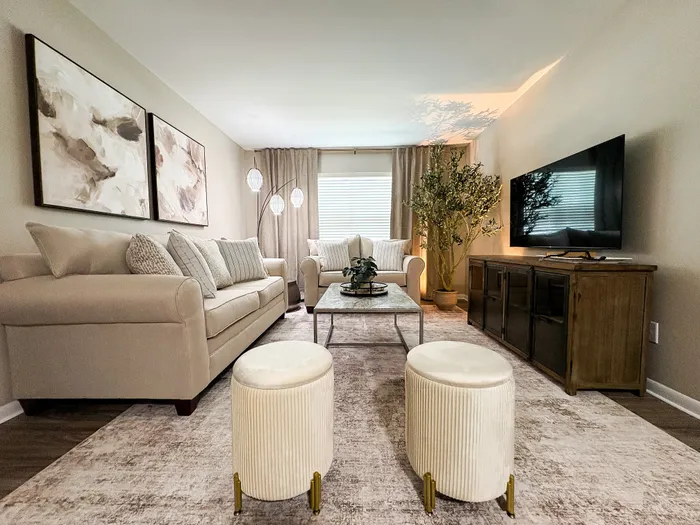 Inviting living room with neutral tones, decorative art, cozy seating, and modern entertainment setup.