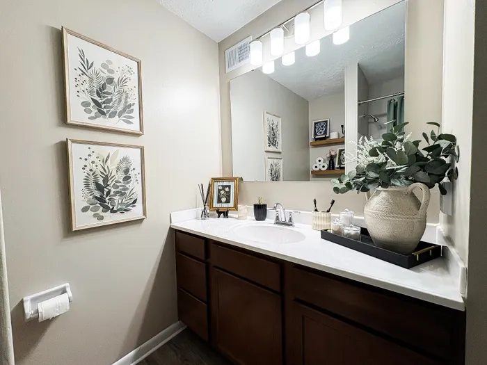 Elegantly designed bathroom with modern fixtures, decorative artwork, and lush greenery accents.