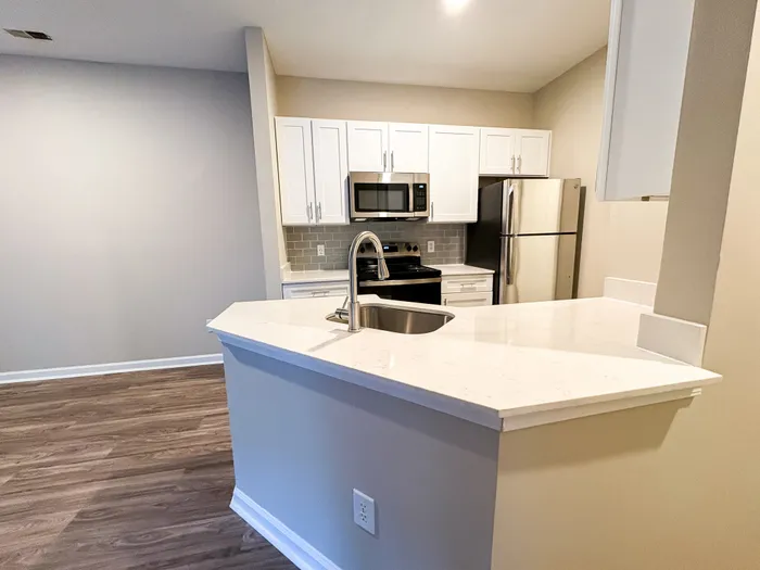Modern kitchen with sleek stainless steel appliances, quartz countertops, and elegant white cabinetry.