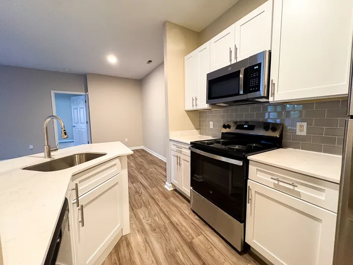 Modern kitchen with sleek white cabinetry, stainless steel appliances, and elegant wood flooring, ideal for culinary creativity.