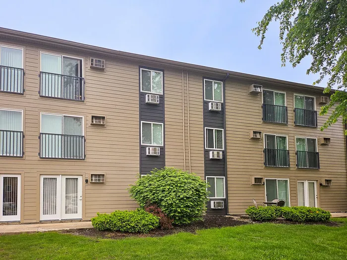 Charming apartment building exterior with modern balconies, surrounded by lush greenery, offering a serene living environment.