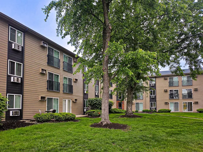 Charming apartment complex surrounded by lush greenery, featuring modern three-story buildings.