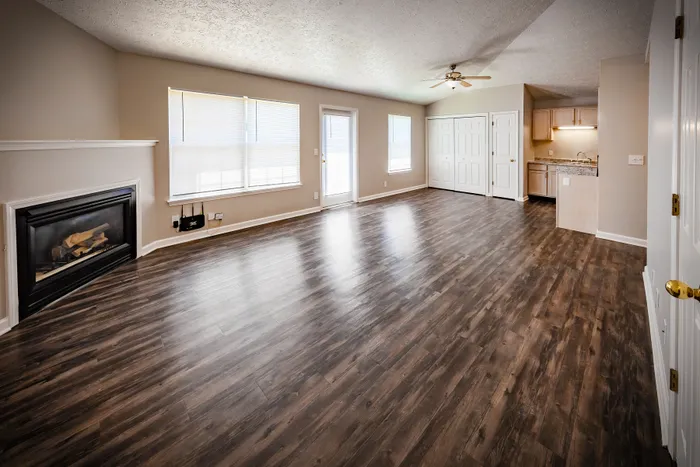Spacious living area featuring elegant hardwood floors, a cozy fireplace, and abundant natural light, perfect for stylish living at Cypress Square Apartments.