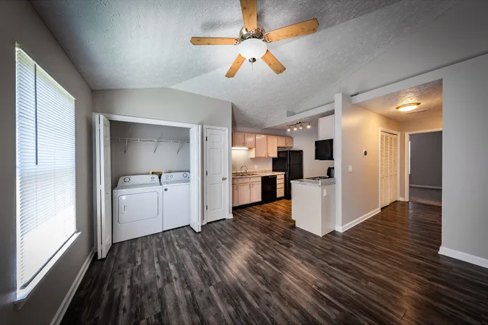 Spacious open-plan apartment with modern kitchen, in-unit washer and dryer, and stylish wood flooring at Cypress Square Apartments.