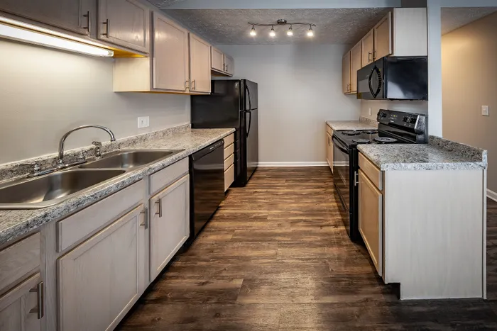Modern kitchen with elegant granite countertops, sleek black appliances, and stylish wooden cabinets at Cypress Square Apartments.