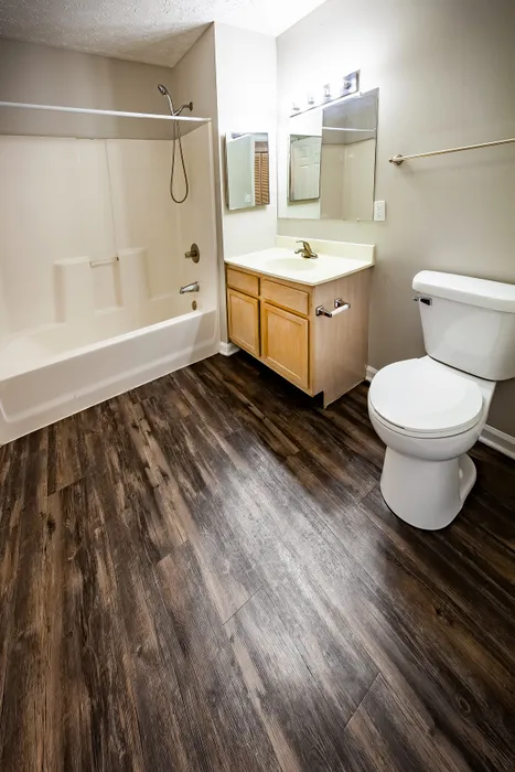 Modern bathroom with elegant wood flooring, spacious tub, and sleek vanity, offering a luxurious and serene retreat at Cypress Square Apartments in Lafayette, IN.