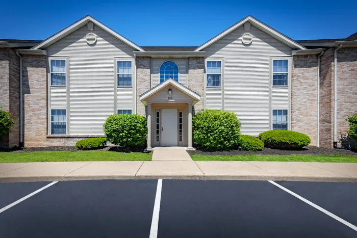 Charming apartment building exterior with welcoming entrance, well-maintained brick facade, and lush greenery at Cypress Square Apartments in Lafayette, IN.