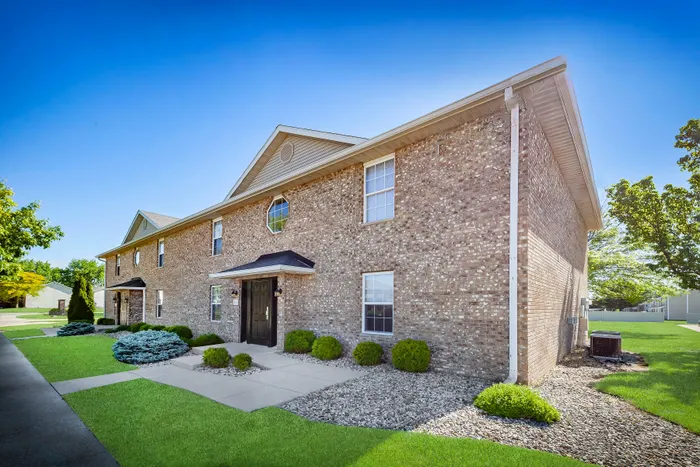 Charming brick apartment building with manicured landscaping and a welcoming entrance.