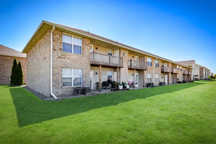 Charming apartment community exterior with beautiful green lawn, private balconies, and a welcoming ambiance.