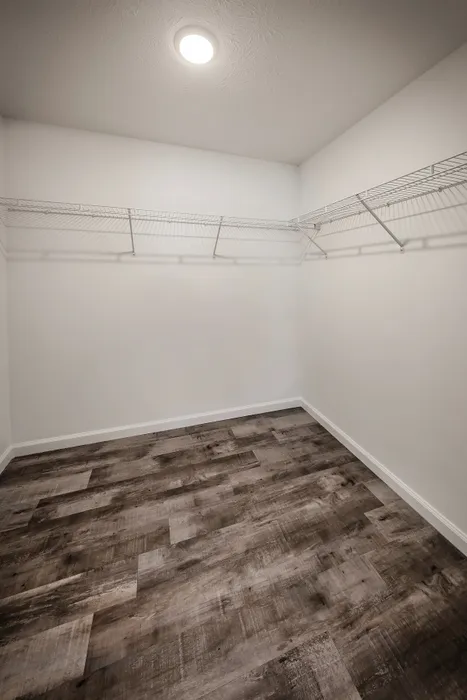 Spacious walk-in closet with modern laminate flooring and ample shelving, ideal for organized storage solutions.