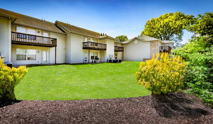 Inviting apartment community with charming balconies, lush green lawn, and vibrant landscaping.