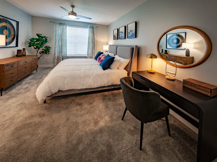 Chic bedroom with elegant modern decor, featuring a plush bed, stylish artwork, and a sleek workspace with a cozy chair.