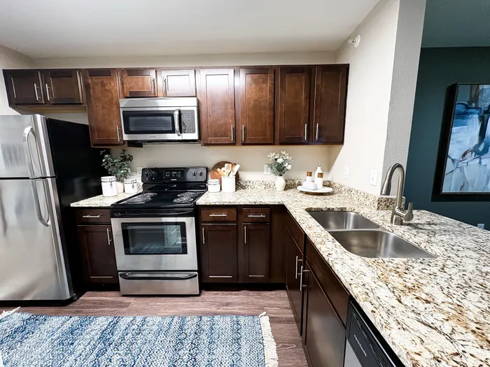 River Crossing modern kitchen with stainless steel appliances, rich wooden cabinets, and elegant granite countertops.