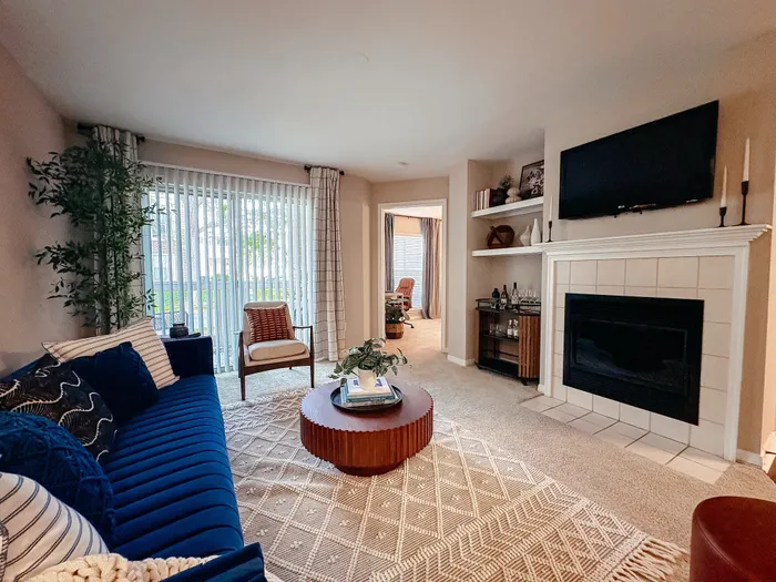 River Crossing elegant living room with plush blue sofa, chic coffee table, modern fireplace, and abundant natural light from large windows.