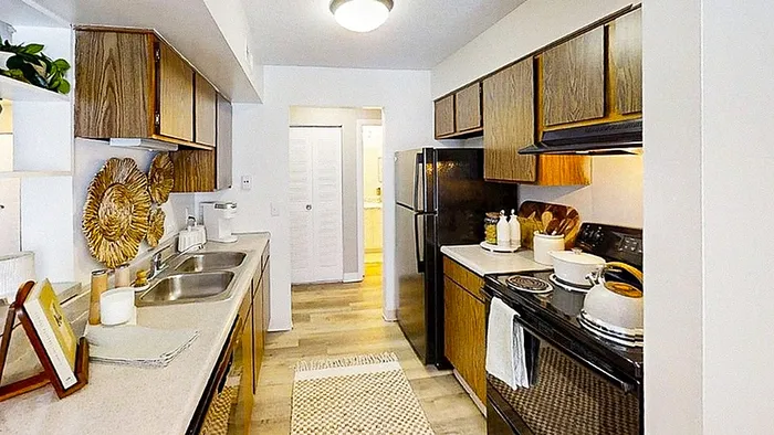 Charming kitchen with warm wooden cabinets, modern appliances, and sleek countertops in a cozy apartment.