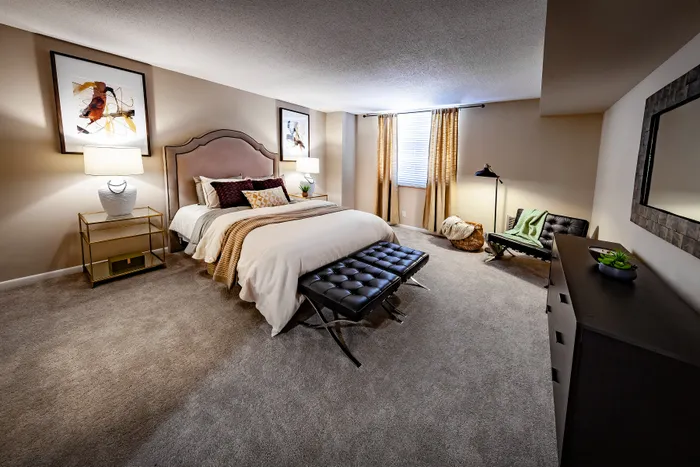 Elegant bedroom with plush carpet, featuring a luxurious bed, stylish lighting, and chic decor, offering a serene and inviting atmosphere.