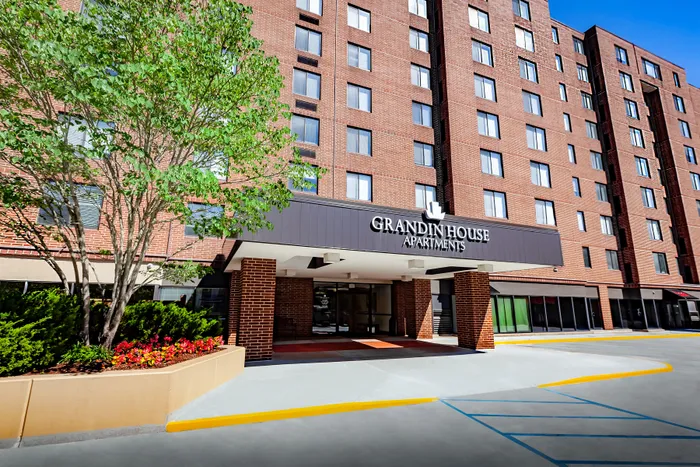 Elegant brick exterior of Grandin House Apartments with lush landscaping and modern entrance.
