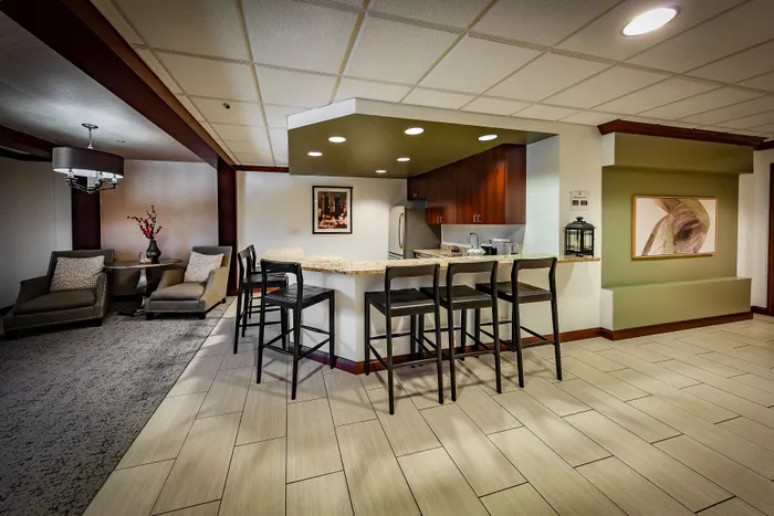 Modern resident lounge featuring a stylish bar counter with sleek seating, cozy seating area with plush chairs, and contemporary decor creating a welcoming atmosphere.