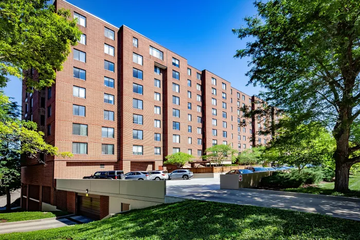 Charming red-brick apartment complex surrounded by lush greenery, offering serene living with ample parking and natural beauty.
