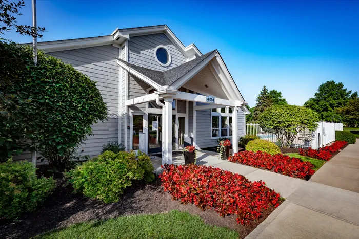 Charming leasing office entrance with manicured landscaping and vibrant red flowers, highlighting a welcoming, serene atmosphere.