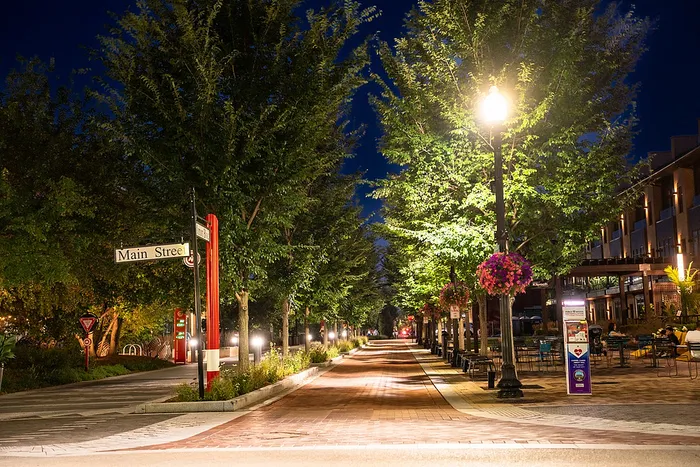 Main Street Carmel Indiana at night, tree-lined brick walkway with string lights on the Monon Trail.