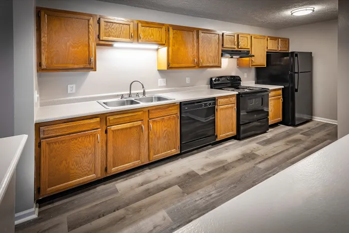 Elegant kitchen with natural wood cabinetry, sleek countertops, and modern black appliances, complementing the stylish laminate flooring.