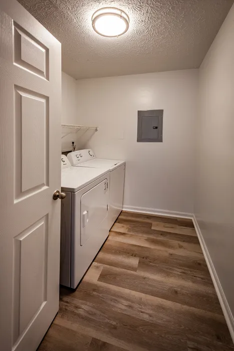 Modern laundry room with a sleek washer and dryer, enhanced by elegant wood flooring and soft neutral walls.