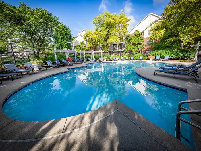 Inviting outdoor pool area with elegant loungers amidst lush greenery and vibrant flowers, perfect for relaxation and leisure.