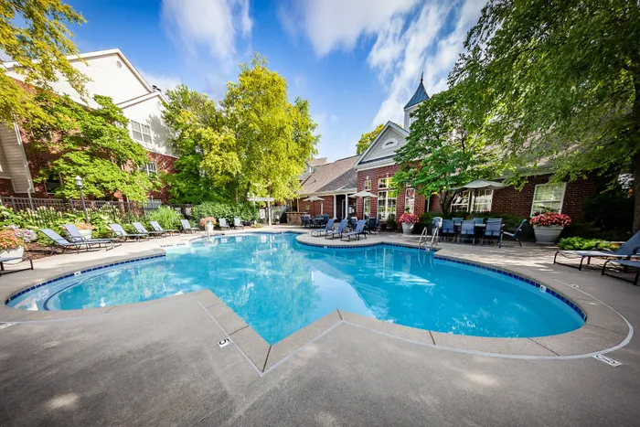 Luxurious apartment complex with a stunning outdoor pool surrounded by lush greenery and elegant lounge chairs for ultimate relaxation.