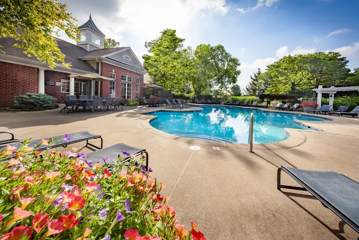 Inviting outdoor pool area with vibrant flowers and plush lounge chairs, perfect for relaxation under sunny skies.
