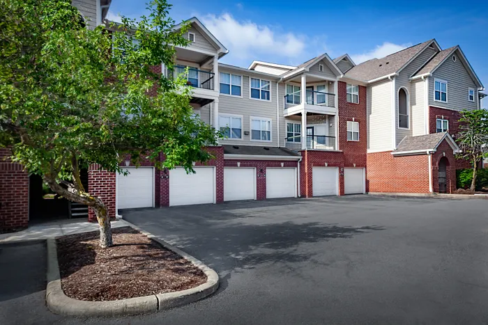 Charming apartment complex with elegant brick and siding facade, featuring multiple balconies and spacious parking area.