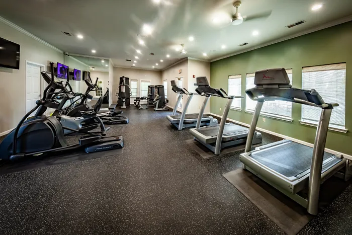 Modern apartment gym with state-of-the-art treadmills, ellipticals, and strength training equipment in a bright, inviting space.
