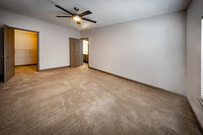 Spacious and inviting room with plush carpet, ceiling fan, and ample closet space, perfect for comfort and style.