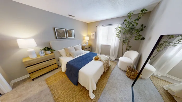 Pebble Point inviting bedroom with elegant decor, featuring a plush bed with blue and white linens, stylish side tables, and natural light streaming through large windows.