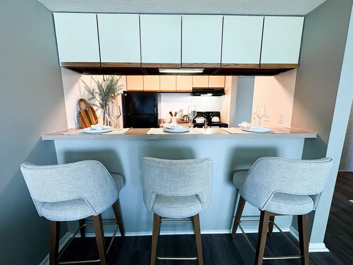 Modern kitchen featuring a cozy breakfast bar with stylish seating, elegant table settings, and sleek cabinetry.