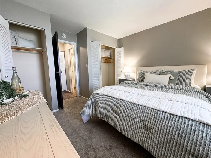 Inviting bedroom with soft lighting, plush bedding, and ample closet space, perfect for relaxation.