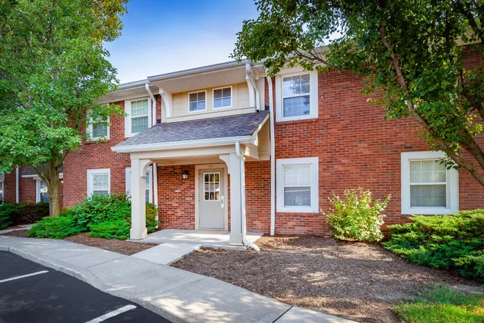 Main Street on the Monon Apartments - Charming brick townhouse exterior with lush greenery and a welcoming entrance.