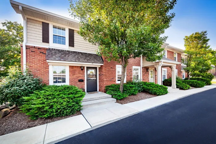 Main Street on the Monon Apartments - Charming townhouse featuring classic red brick exterior with lush green landscaping and inviting entrance.