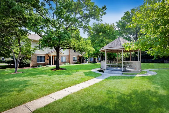 Main Street on the Monon Apartments - Charming residential area with lush green lawns, a serene gazebo, and inviting brick apartment homes.