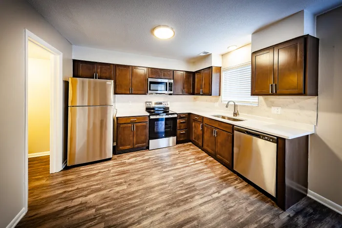 Main Street on the Monon Apartments - Modern kitchen with rich wooden cabinets, sleek stainless-steel appliances, and elegant countertops.