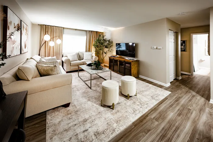 Main Street on the Monon Apartments - Elegant modern living room with plush beige sofas, stylish floor lamp, cozy area rug, and sleek wooden flooring.