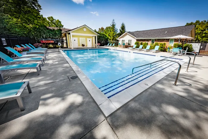 Inviting outdoor pool area with sleek lounge chairs and lush greenery, perfect for relaxation and soaking up the sun.